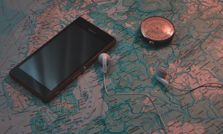 Earphones and phone on map next to compass