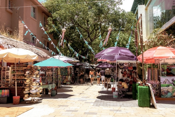 A colourful local market street with umbrellas and craft stalls