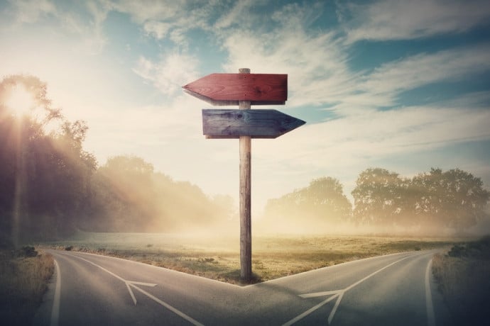 A signpost at a crossroads in misty countryside, representing the uncertainty of DIY travel