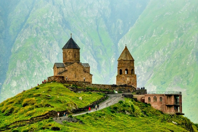 Gergeti Trinity Church on a green hillside in Georgia, one of our top spring adventures