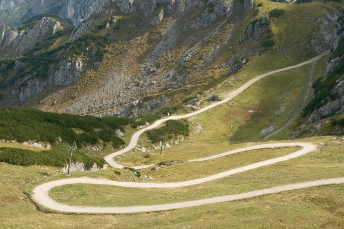 A winding trail through green mountain slopes, representing off-the-beaten-track travel